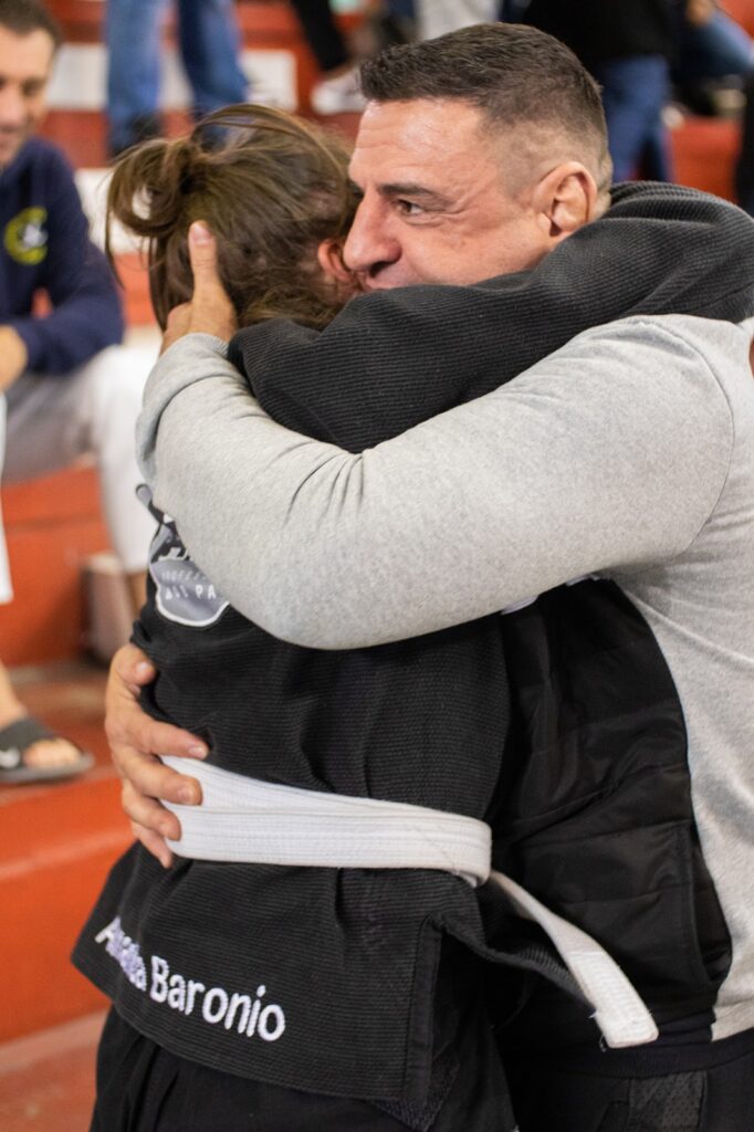 Campeã Brasileira de Jiu-Jitsu Amanda Baronio é abraçada pelo treinador Bobzão em competição da faixa branca.